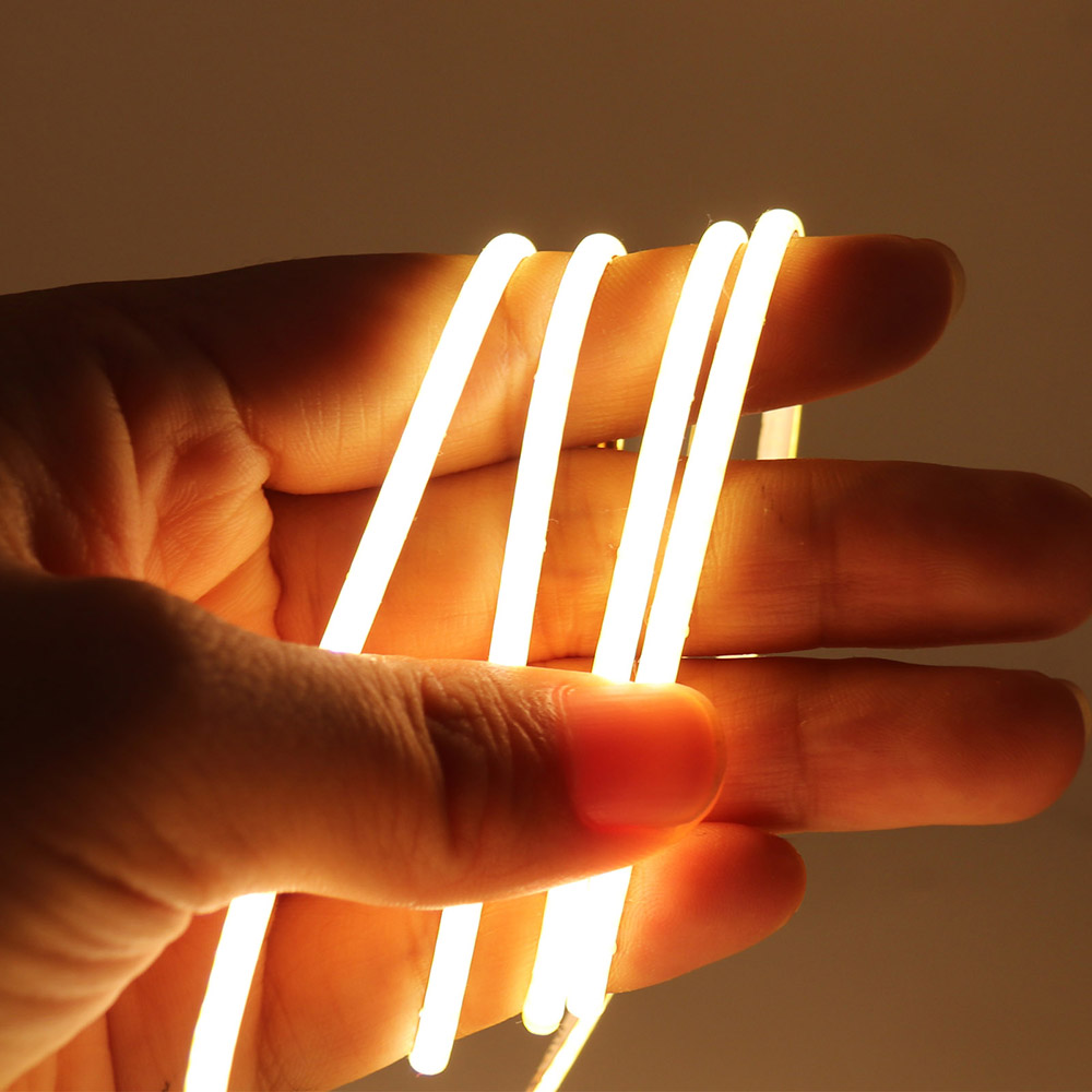 A hand holding flexible, bright white LED strip lights, showcasing their soft and versatile design for various lighting applications.