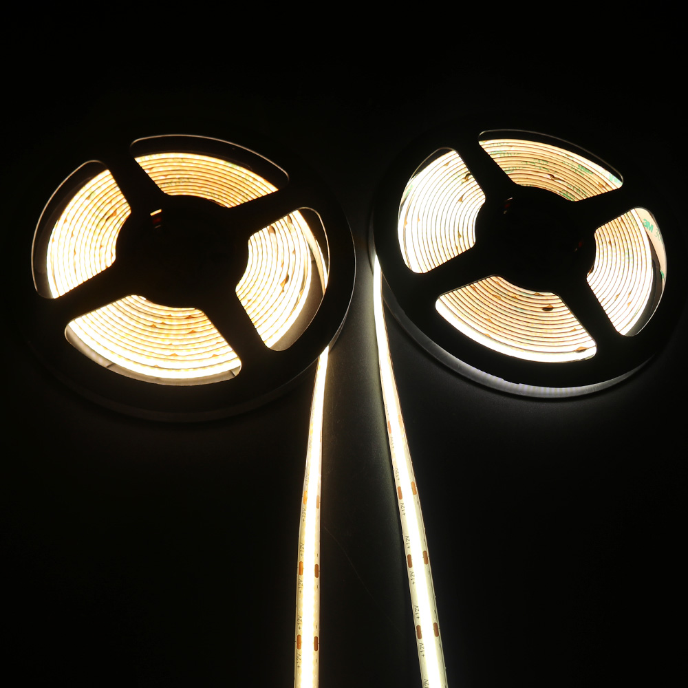 Two reels of COB LED strip lights emitting warm white and cool white lighting, ideal for ambient indoor applications and precise lighting customization.