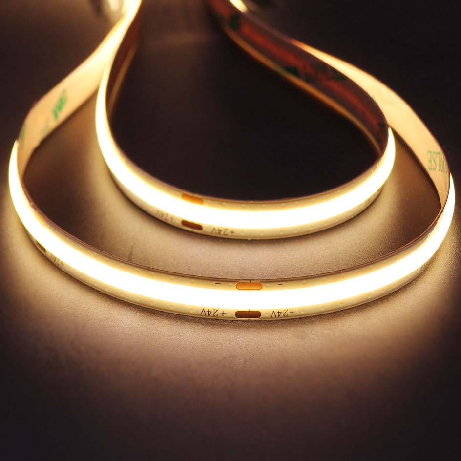 Close-up of a flexible 24V COB LED strip light emitting a continuous warm white glow, ideal for accent and ambient lighting in modern interiors.