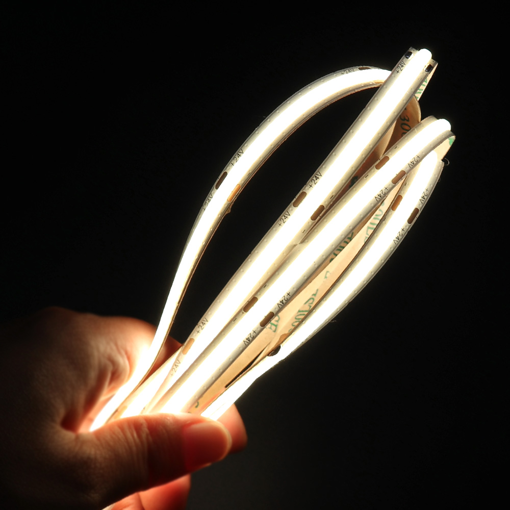 Hand-holding multiple flexible LED strips, emitting bright, uniform light for versatile lighting applications."