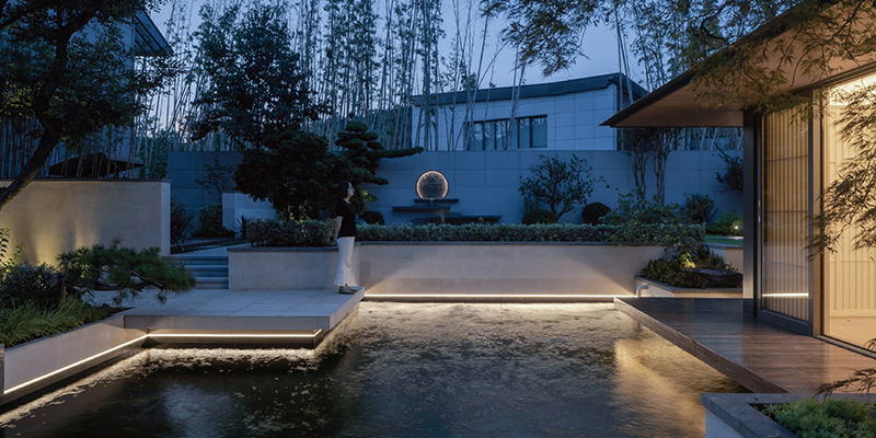 Outdoor lighting, garden, LED LED strip lights illuminating the edge of a tranquil garden water feature at dusk