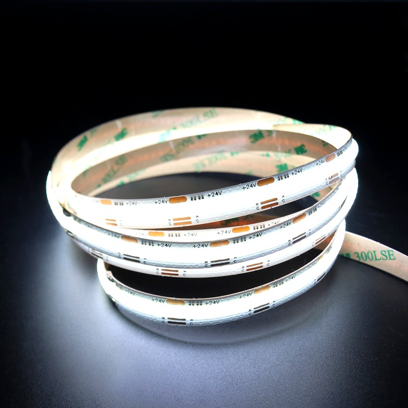 Cool white 24V COB LED strip light coiled on a black surface, with visible 3M 300LSE adhesive backing for easy mounting in various lighting applications.