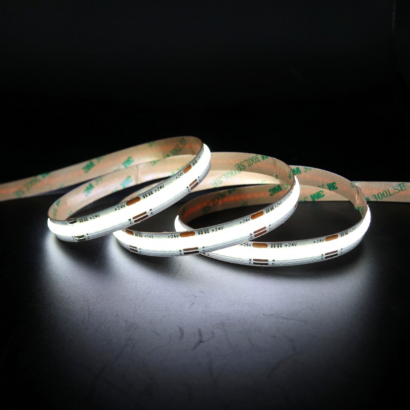 Close-up of a glowing 24V COB LED strip light with 3M adhesive backing, displayed on a black surface for contrast.