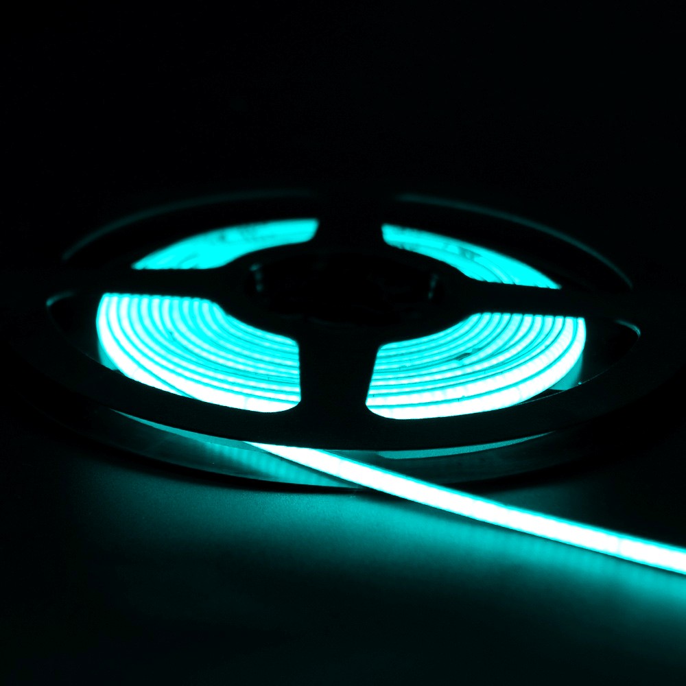 Coiled green neon flex LED strip light glowing brightly in the dark, mounted on a black reel with visible light trail on the surface.
