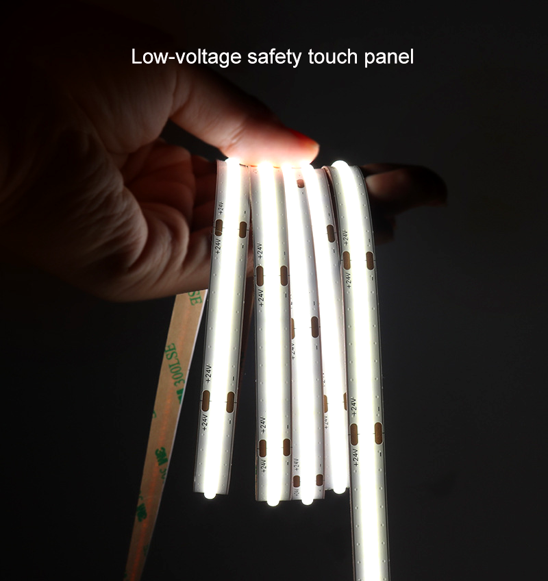 Close-up of a hand holding low-voltage COB LED strip lights glowing white, demonstrating safe-touch panel in operation.
