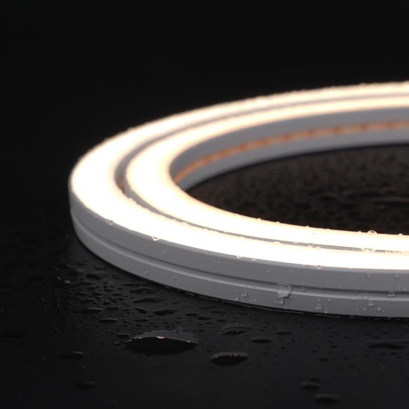 Close-up side view of a flexible neon LED strip light, glowing with a soft white light and surrounded by water droplets, emphasizing its waterproof design