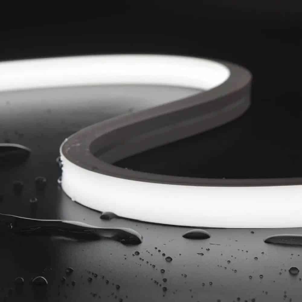 Flexible neon LED strip light glowing with a smooth, continuous white light, surrounded by water droplets.