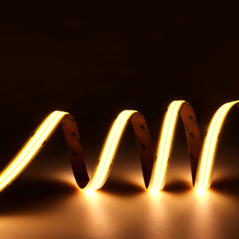 Warm white COB LED strip light arranged in a wave shape and glowing brightly on a dark background with 3M adhesive visible.