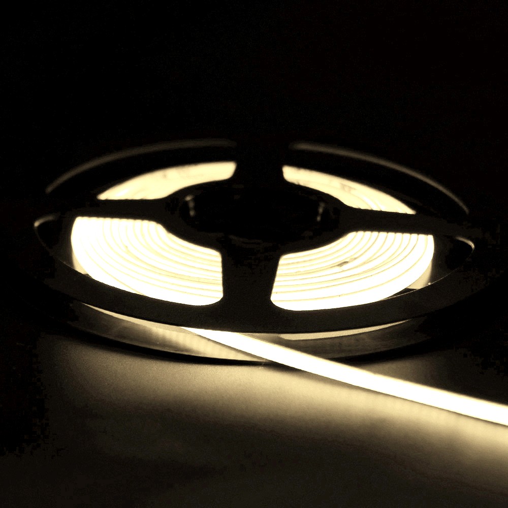 Illuminated white neon flex LED strip light coiled on a black reel, glowing gently in a dark environment.