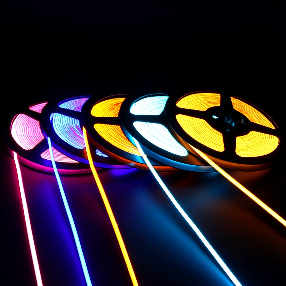 High-brightness RGB COB LED strip lights on reels emitting colorful light, ideal for flexible decorative and ambient lighting installations
