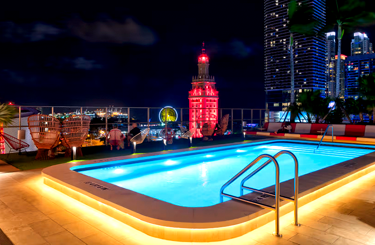 LED strip lights installed around a rooftop swimming pool edge, creating a vibrant and elegant lighting effect at night with city buildings in the background