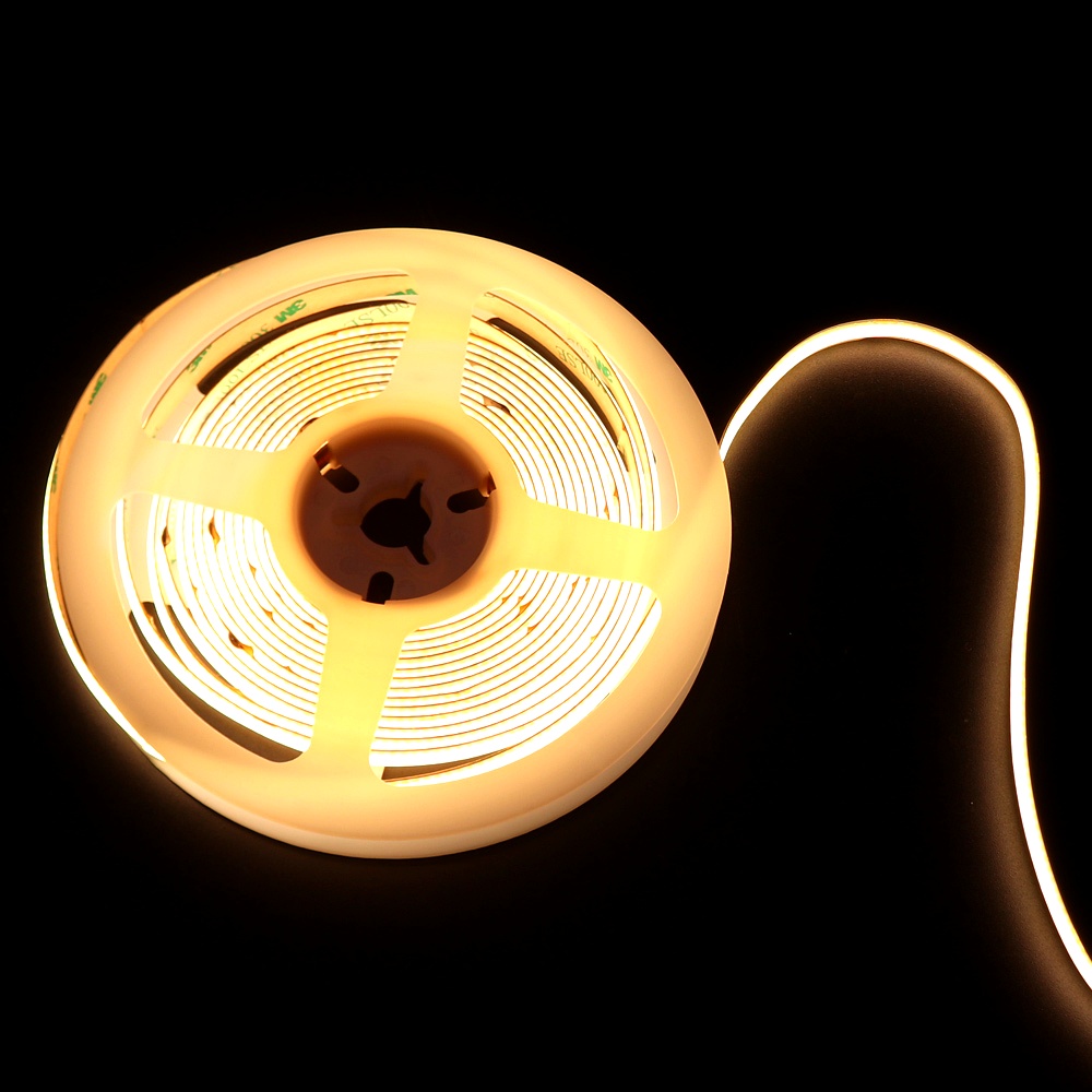 Reel of warm white COB LED strip light glowing on black background, showing flexible and dot-free lighting effect