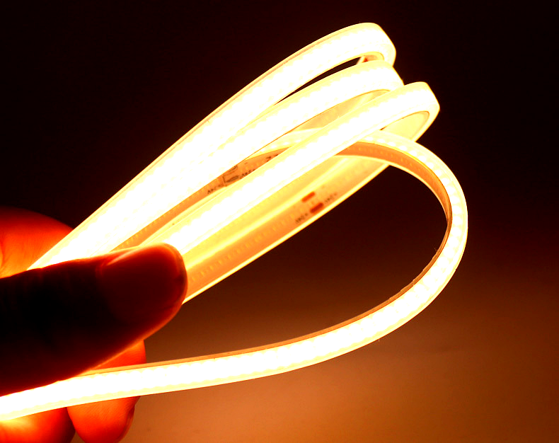 Flexible warm white neon LED strip light glowing in a hand, showcasing soft illumination and high flexibility for indoor accent lighting