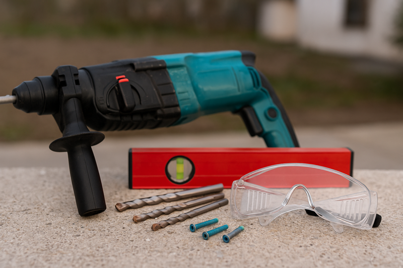 Collection of Tools for Mounting on Concrete: Hammer Drill, Masonry Bits, Concrete Screws, Level, Safety Goggles