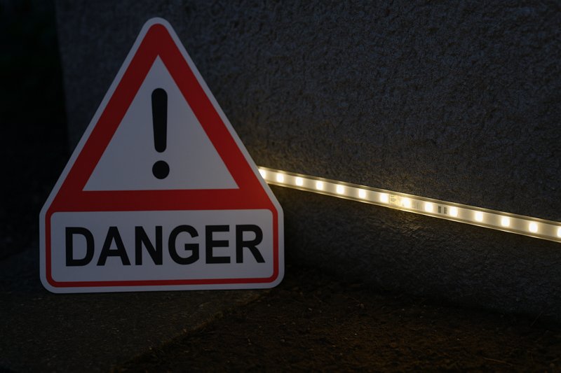 A "danger" or "warning" sign next to a faulty, flickering outdoor LED strip