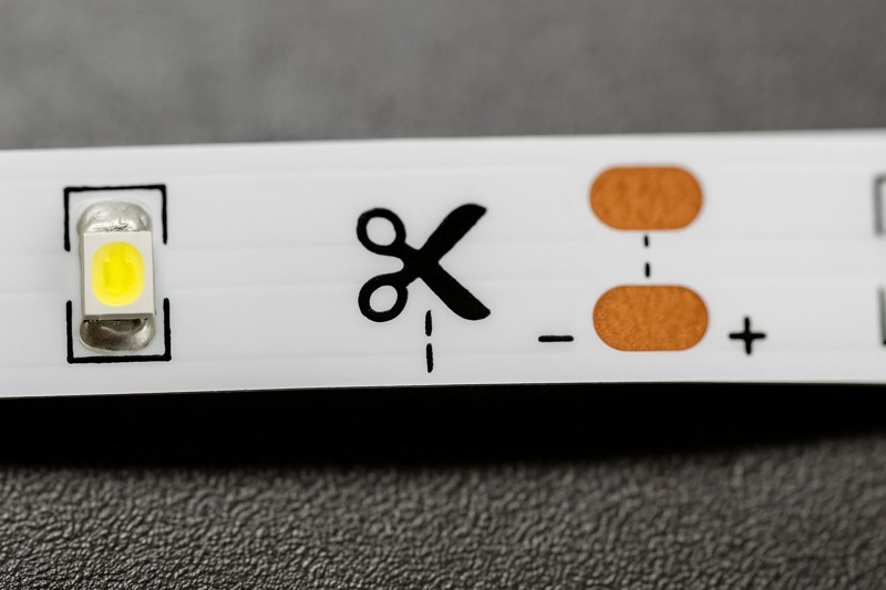 Magnified view of LED strip cut point with scissor icon and copper pads