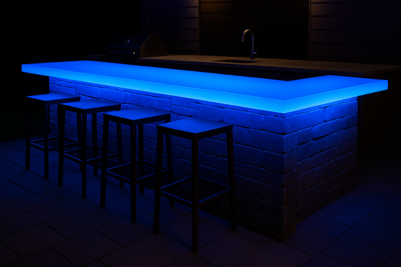 A modern outdoor bar at night, its translucent countertop glowing a brilliant blue from the LED strip installed underneath.