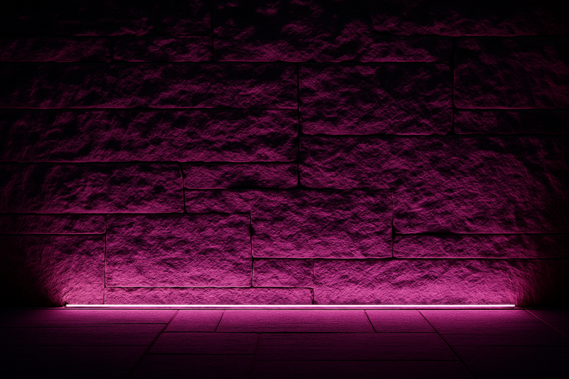 A textured stone wall at night being washed with a subtle, elegant magenta light from a hidden LED strip at its base.