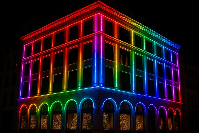 A stunning architectural facade of a commercial building outlined with vibrant, color-flowing LED strip lights for a Christmas display