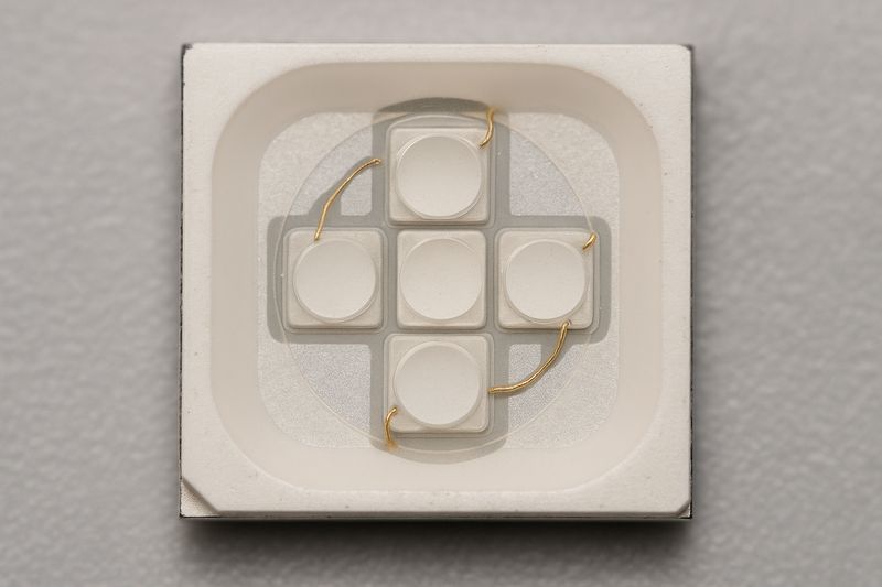 A macro shot of a 5-in-1 RGBWW chip, clearly showing the distinct R, G, B, Warm White, and Cool White diodes.